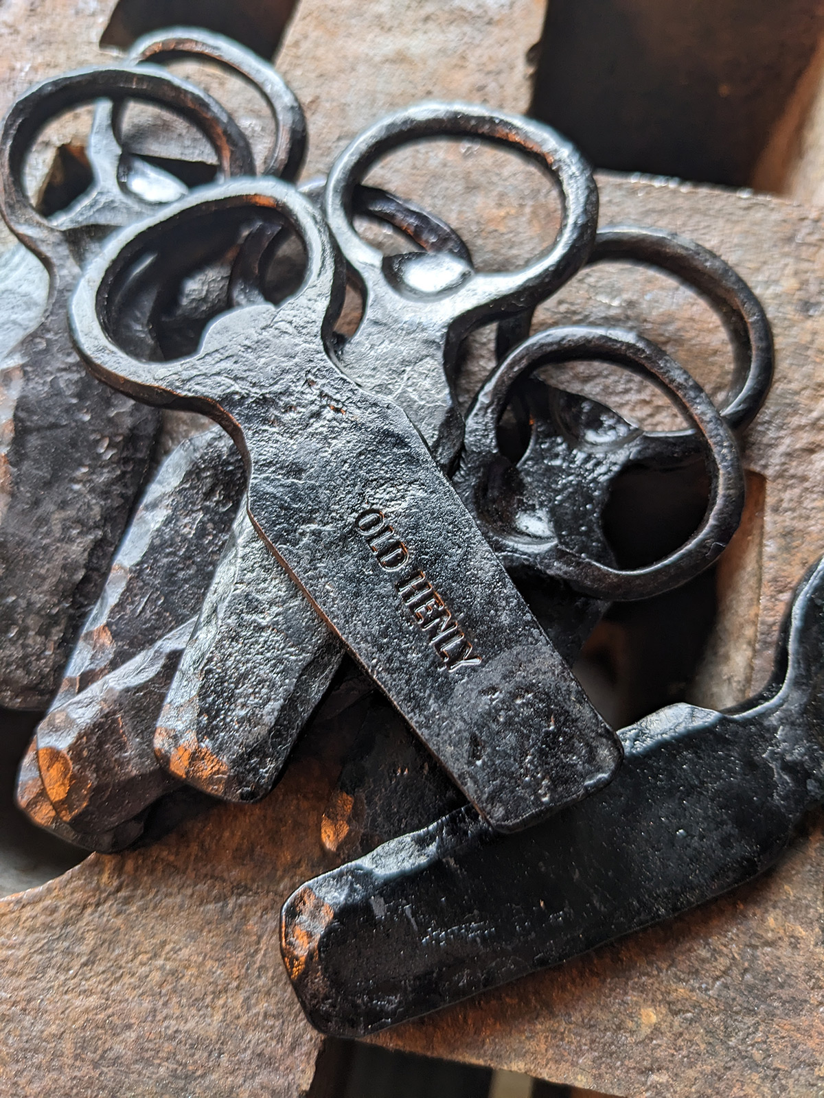 A pile of forged bottle openers showing the Old Henly maker's mark.