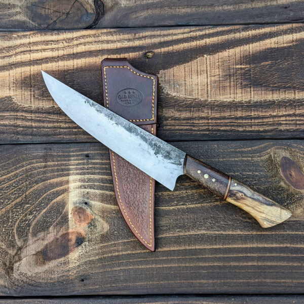 Chef knife laying on a leather scabbard.