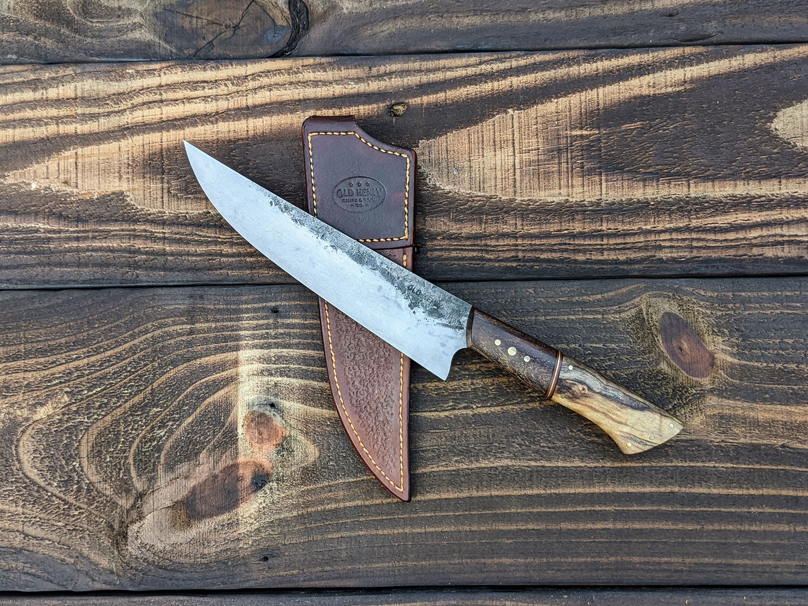 Chef knife laying on a leather scabbard.