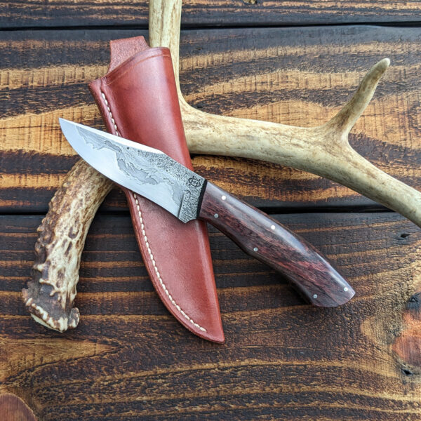 A recurve hunting knife with chainsaw chain damascus cladding.